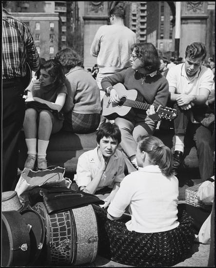 A girl playing the guitar, with two girls in the foreground, Washington Square Park, 1956.