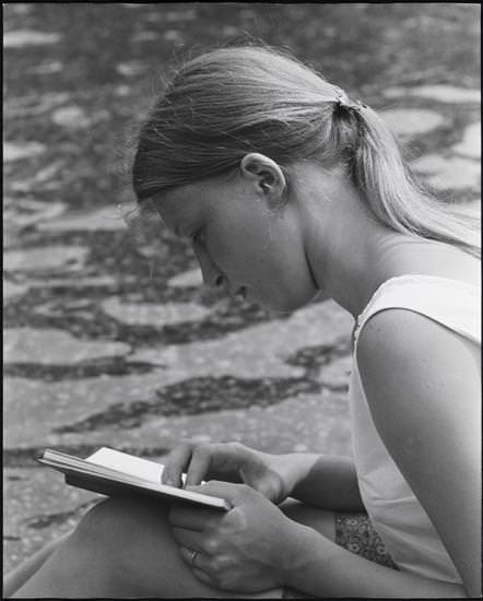 A closeup of a woman with blonde hair reading in Washington Square Park, 1956.