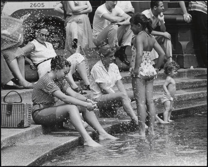 Women with their feet in the fountain, a young girl in a bathing suit, Washington Square Park, 1956.