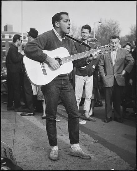 A man playing a 12-string guitar in Washington Square Park, 1956.