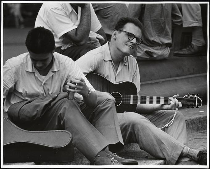 A man with a harmonica sitting with a guitarist in Washington Square Park, 1956.