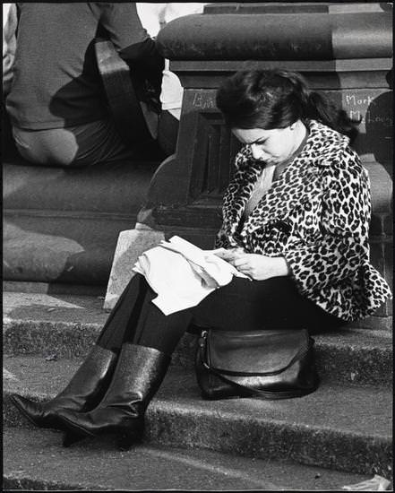 A woman reading on the fountain steps with a guitarist in the background, Washington Square Park, 1956.