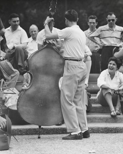 A man playing bass on the fountain steps, Washington Square Park, 1955.