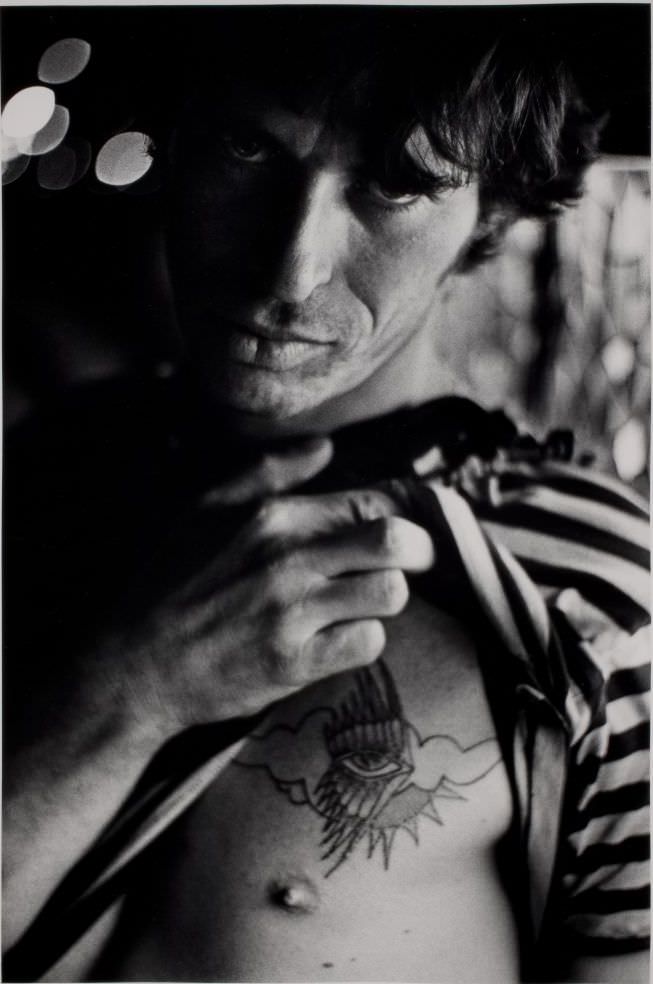 Man in striped shirt showing tattoo.