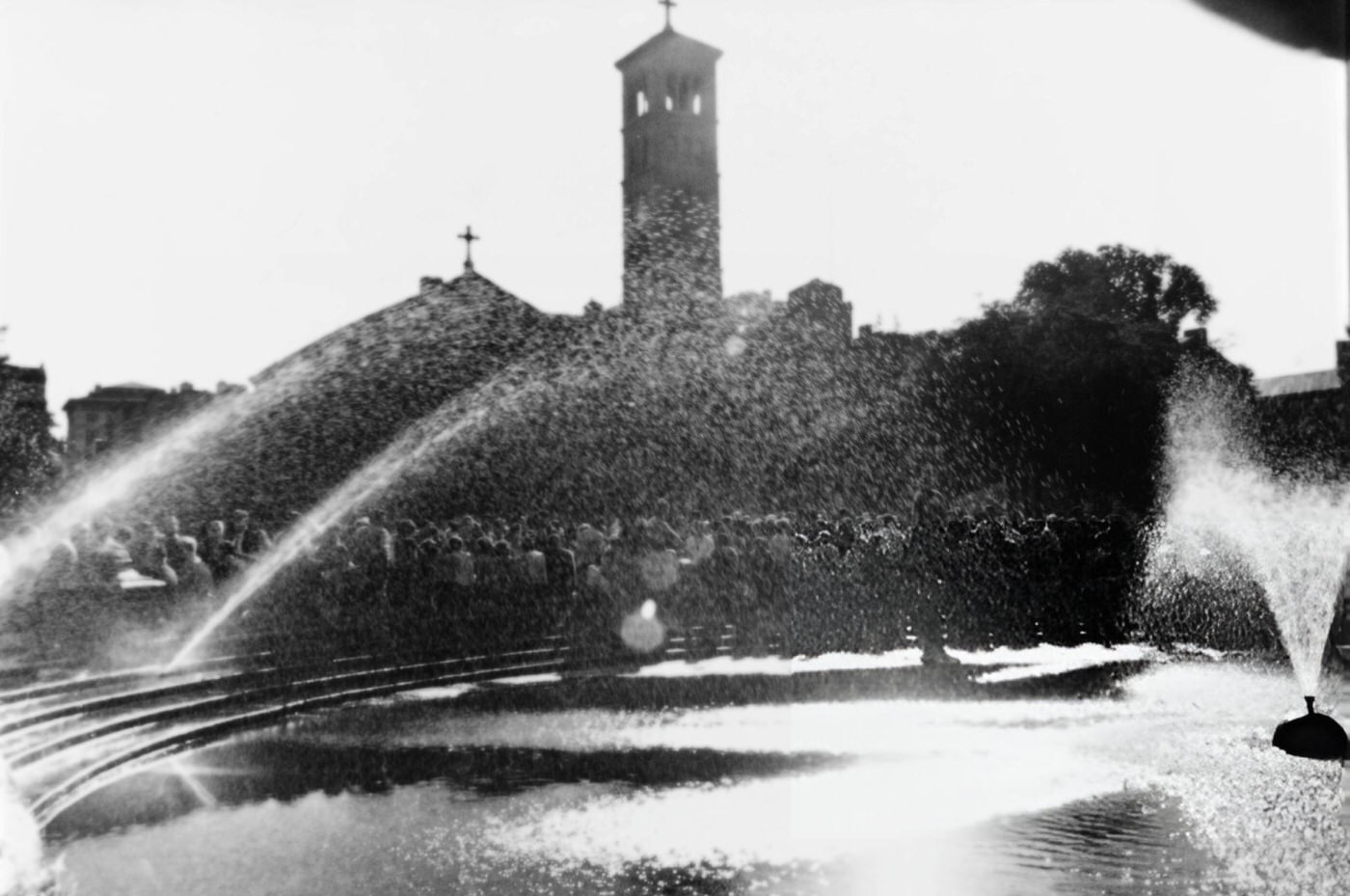 People gathered by the fountain in Washington Square Park with the Judson Memorial Church, 1950s.