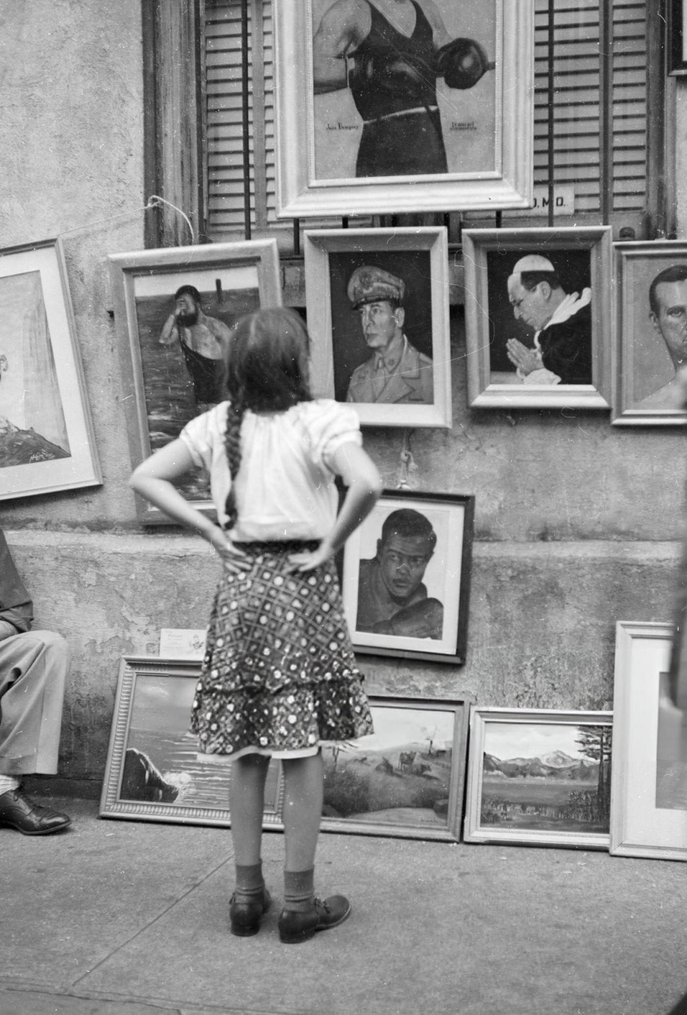 A girl views paintings on sale in Washington Square Park, 1955.