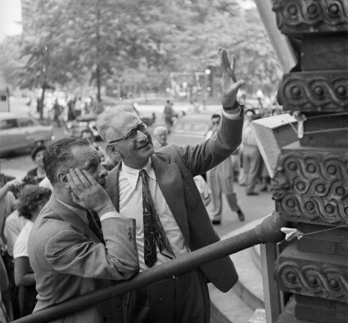 Two men examine paintings at a stall in Washington Square Park, 1955.