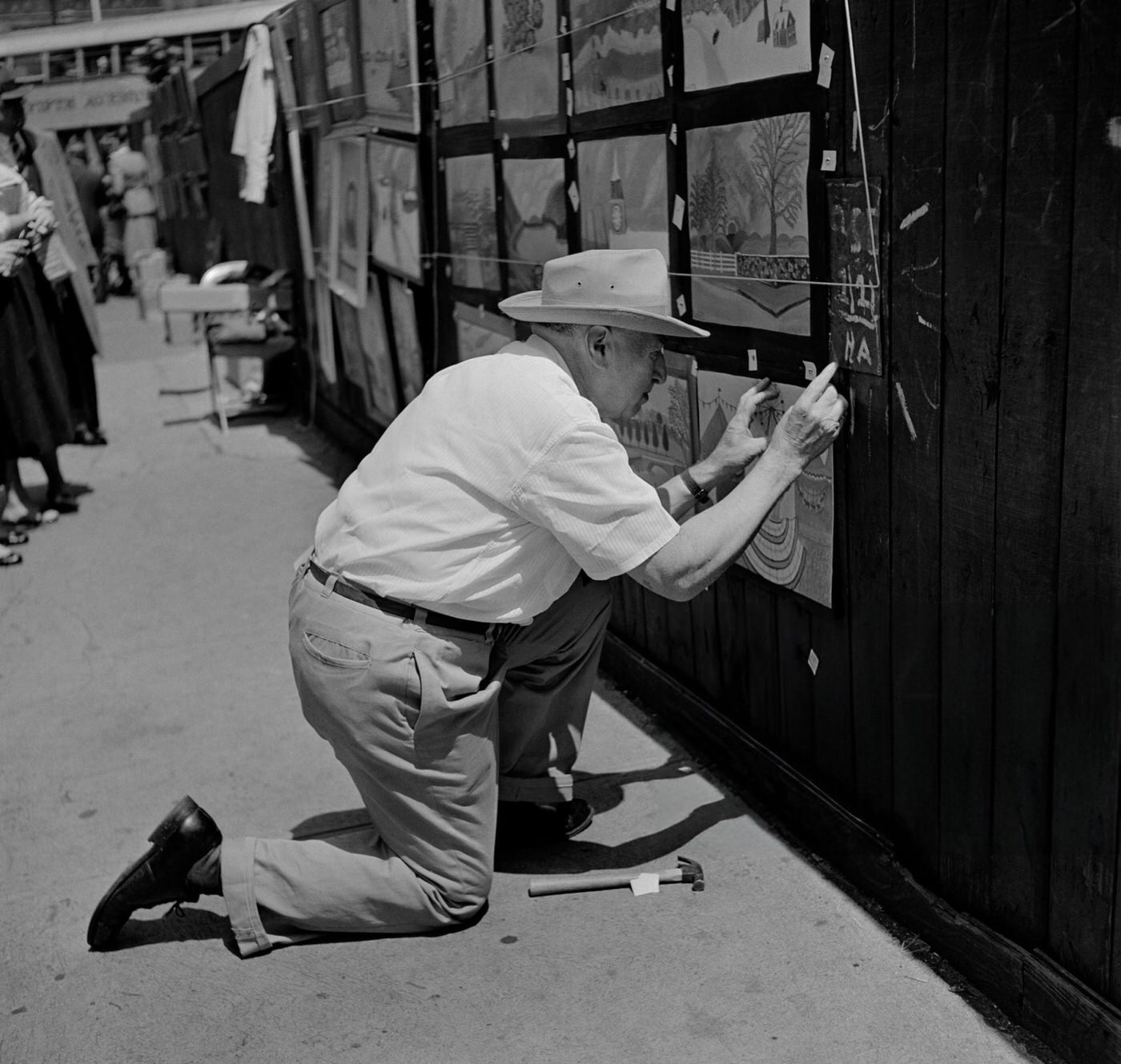 An artist attaches a painting to a wall off Washington Square, 1952.