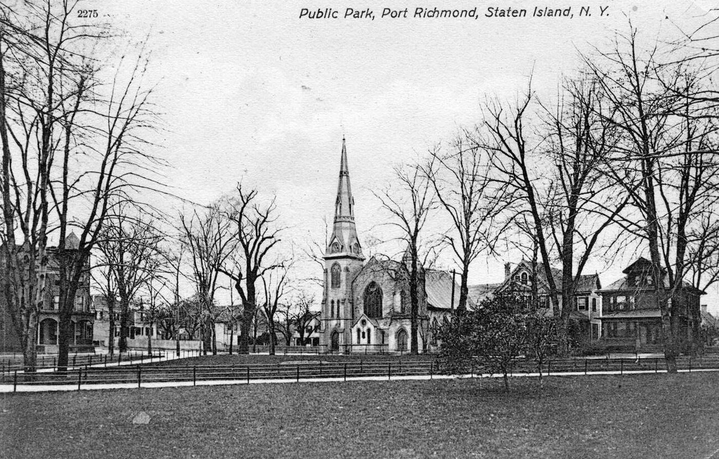 A public park in Port Richmond, with walkways, trees, a church, and residences, 1900.
