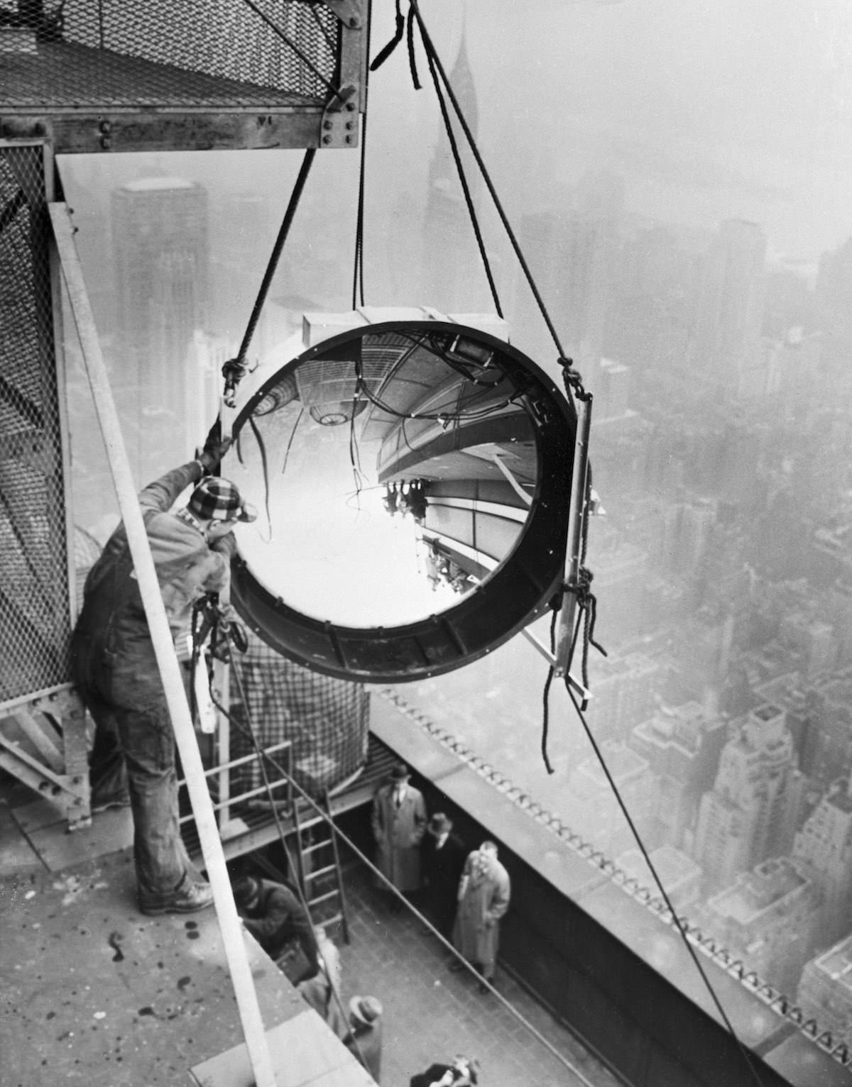 Workmen place one of the new beacon lights on the 90th floor of the Empire State Building, 1956.