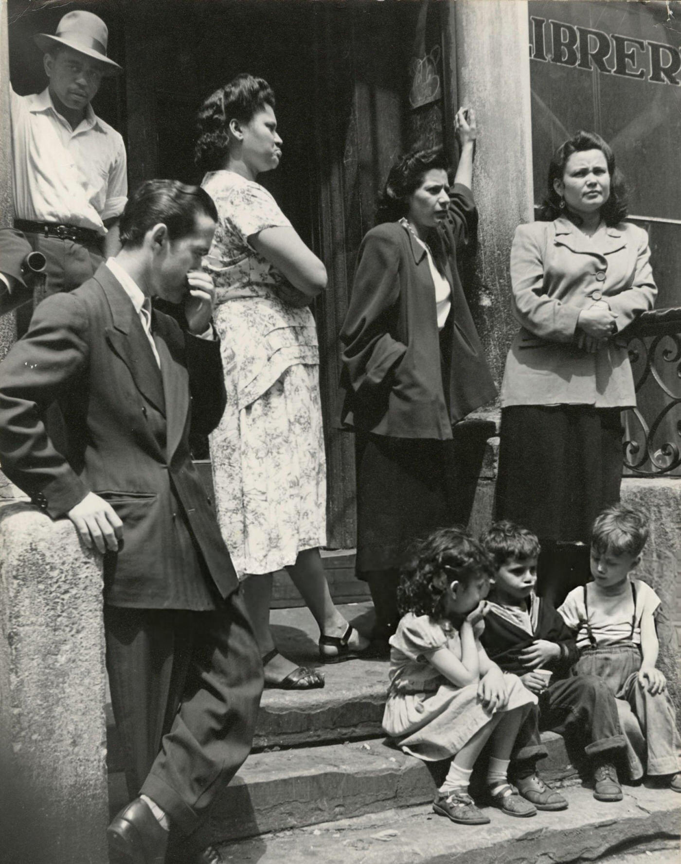 A group of men, women, and children gathered on a stoop in East Harlem, 1940s.