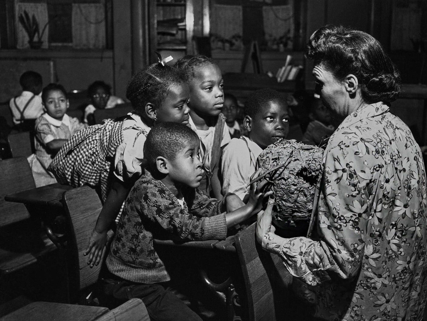 Children feeling the exterior of a hornets' nest held by a teacher in a classroom at a Harlem school, 1948.