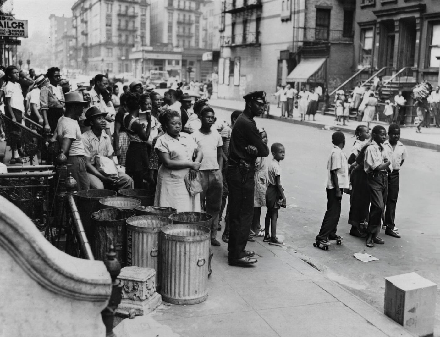 A policeman restrains a crowd at a fire in Harlem, 1948.