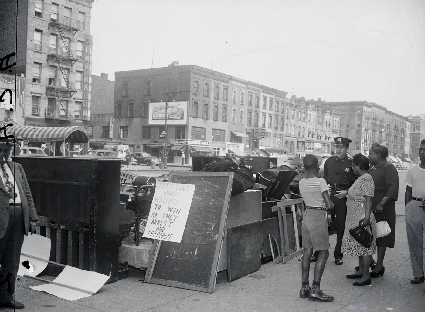 Police officer next to evicted goods from Communist Party Headquarters in Harlem, 1948.