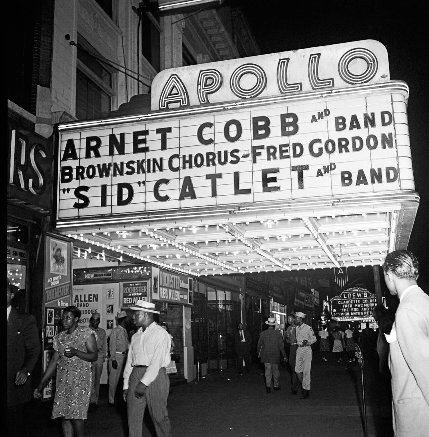 View of the Apollo Theatre marquee at night on West 125th Street in Harlem, 1947.