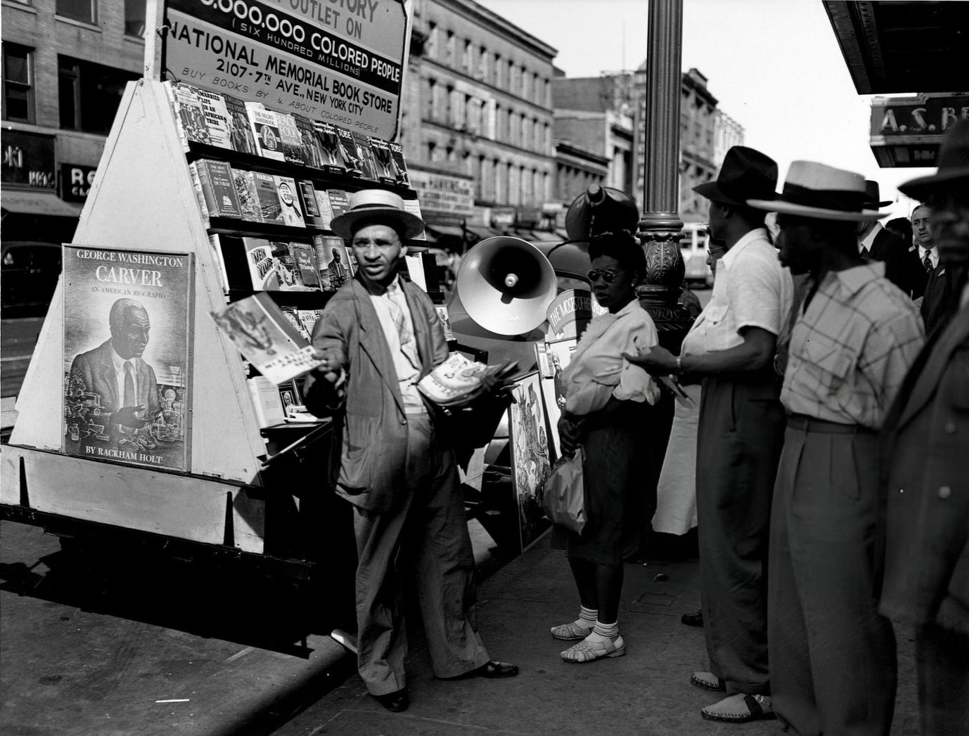 A vendor showing his wares at a bookstall on 125th Street in Harlem, 1943.