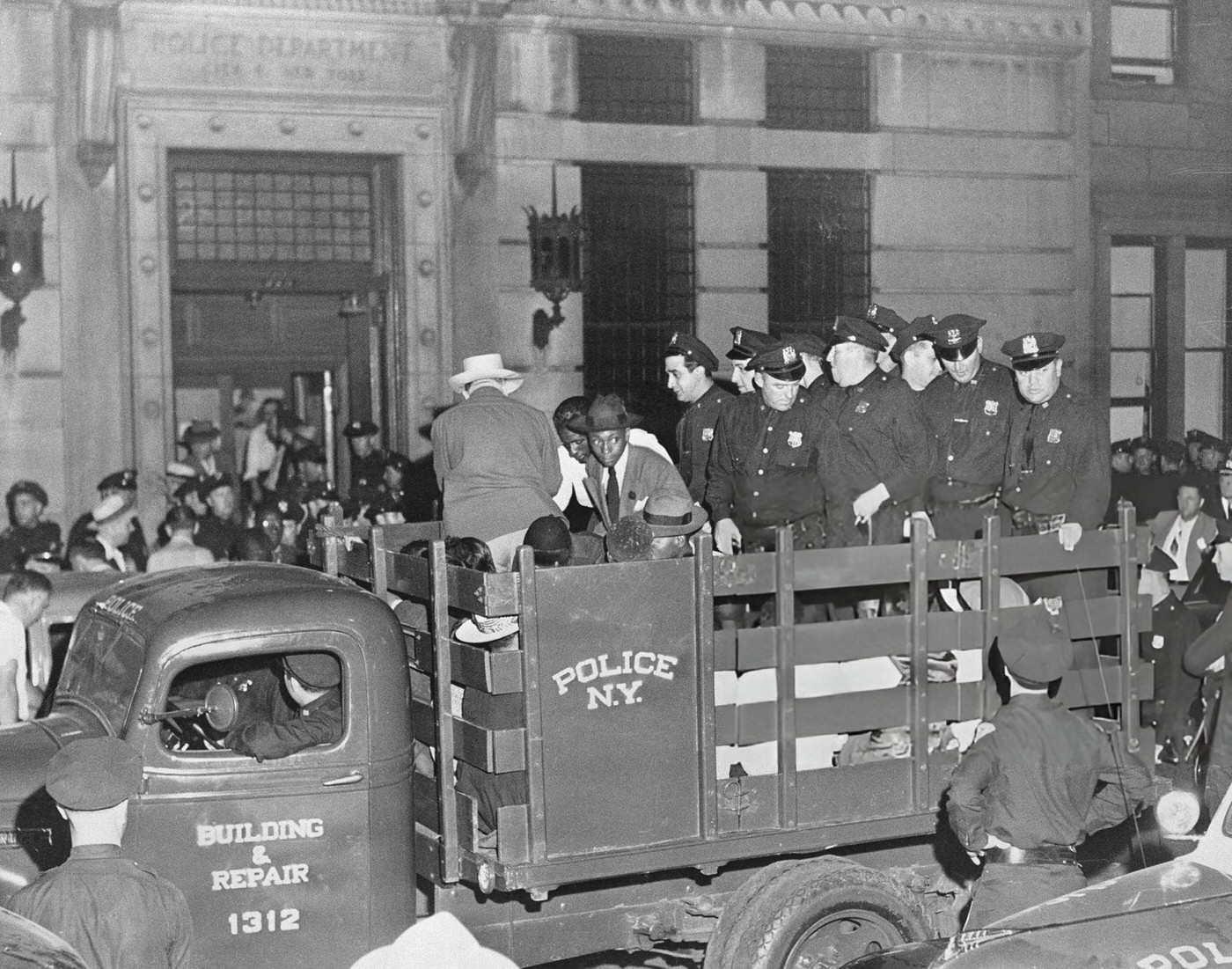 Suspects in a Harlem 'race riot' are herded to a truck by police, 1940s.