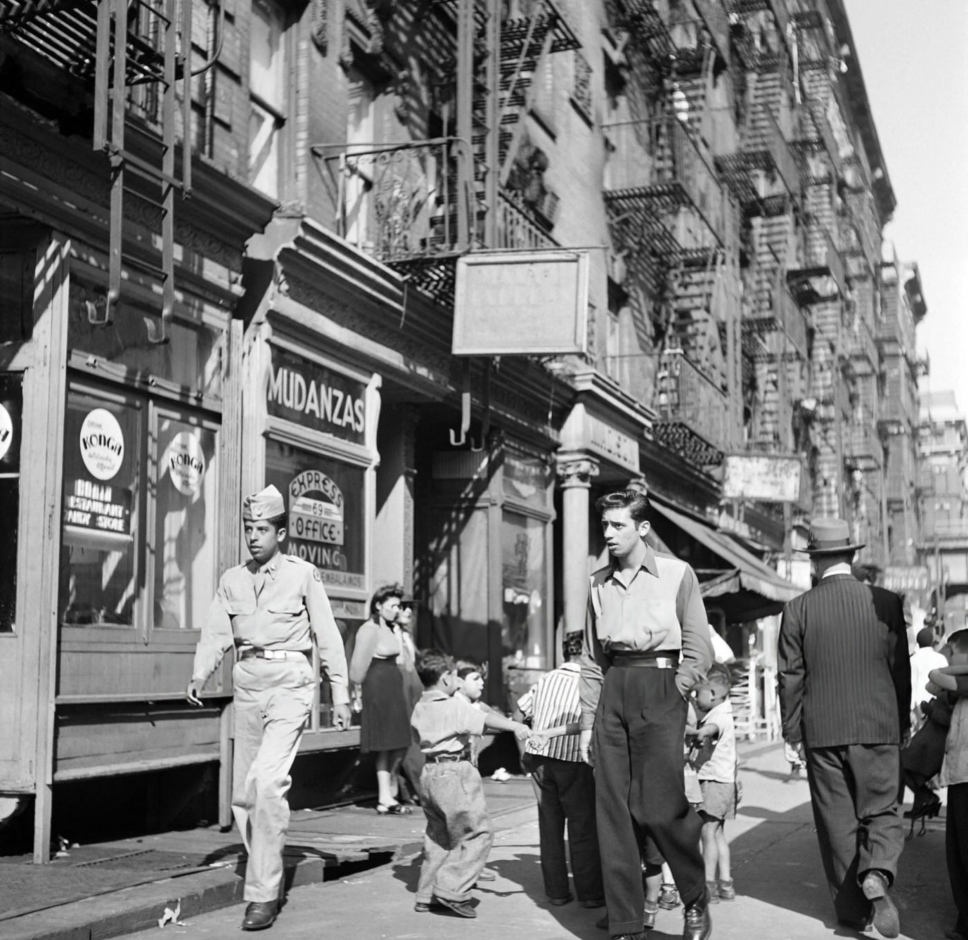 Two young men walk among children playing on the sidewalk in Harlem, Manhattan, 1946.