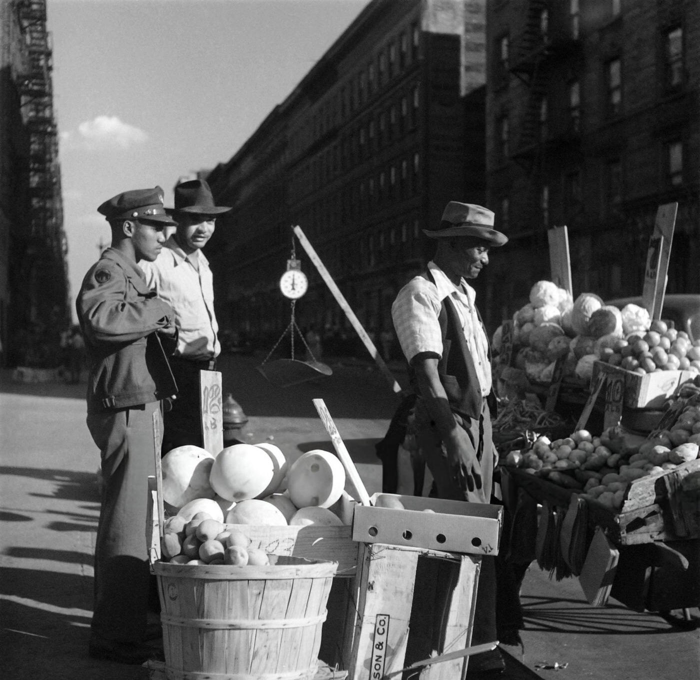 A policeman stands near a street vendor selling fruits and vegetables in Harlem, Manhattan, 1946.