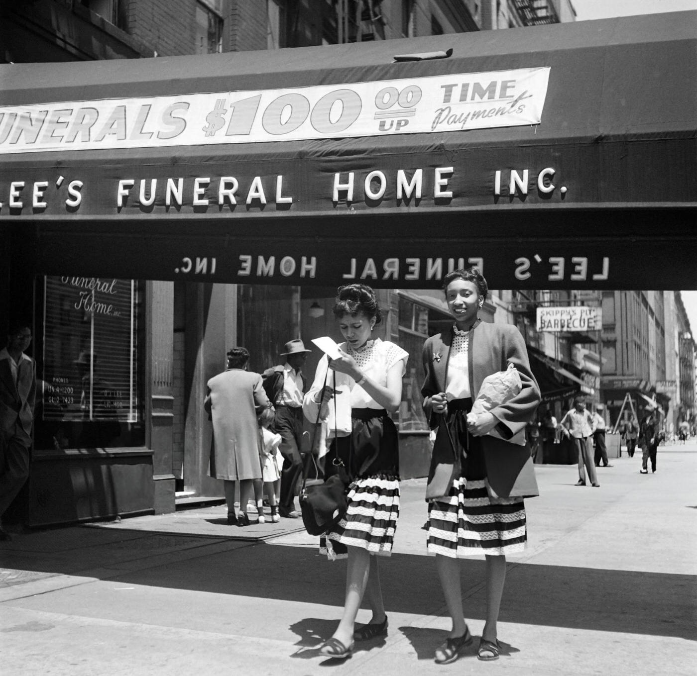 Two girls elegantly dressed in striped skirts walk on a street of Harlem, Manhattan, 1946.