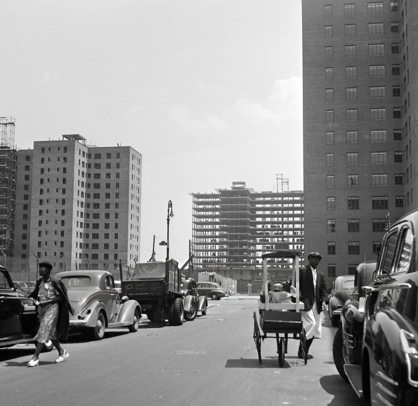A street vendor walks down a street of Harlem where buildings are under construction, 1946.