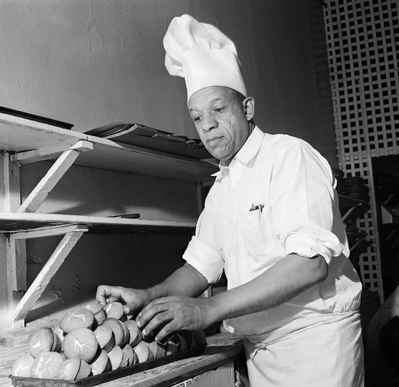 A baker displays cakes in his pastry shop in Harlem, 1946.