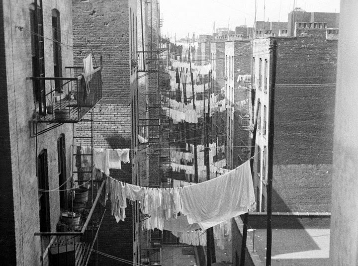A view down an alley with rows of laundry hanging from tenements, New York City, 1930s.