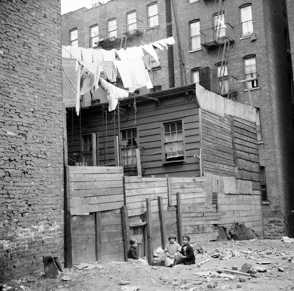 Wooden rear tenements with children playing in dirt, 1935.