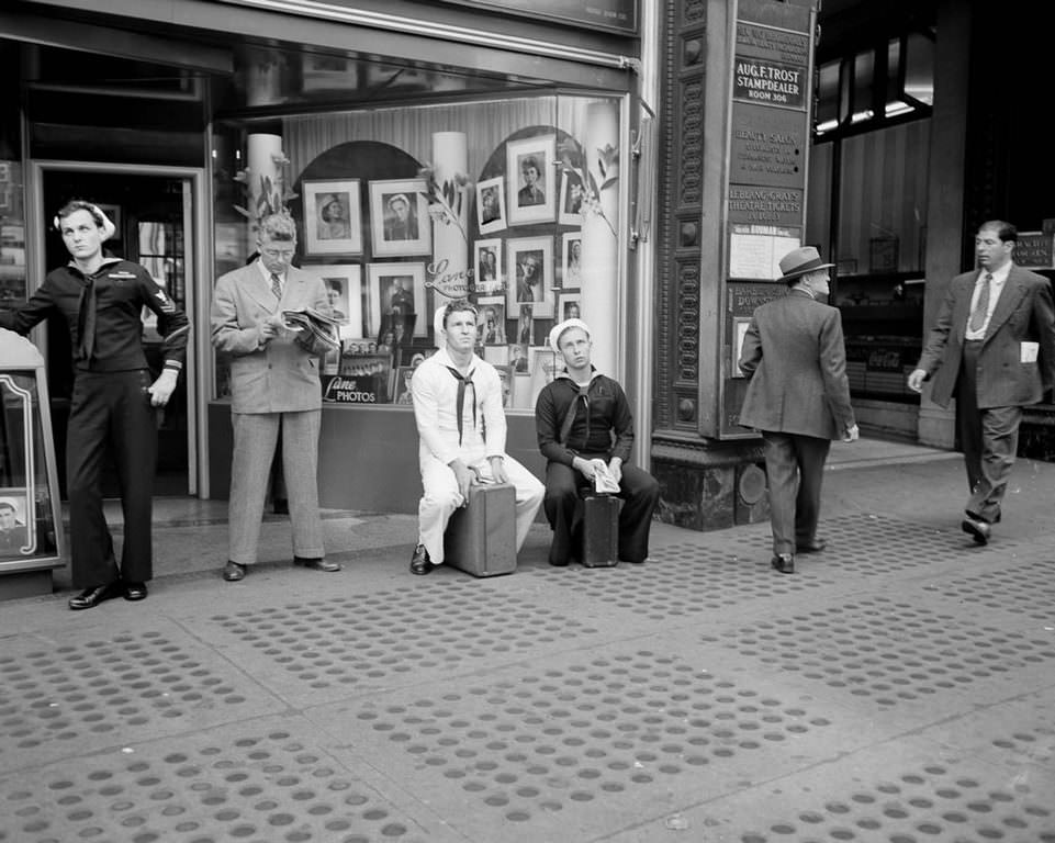 Sailors sit on their briefcases and lean, waiting for more news in one of the most significant developments of World War Two.