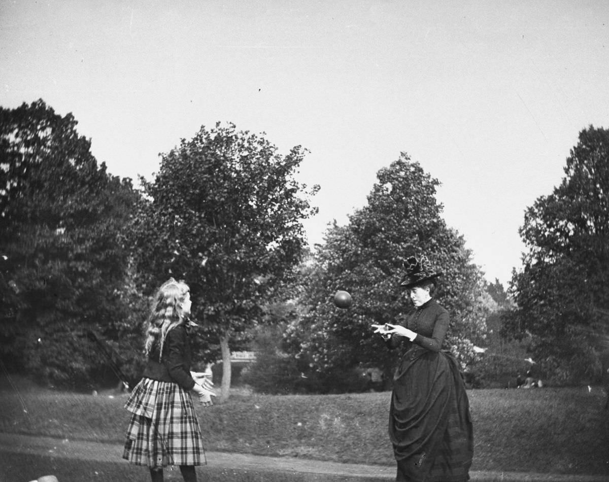 Zelma Levison and her aunt Jo Grimwood throw a ball back and forth on a lawn in Prospect Park, 1886.