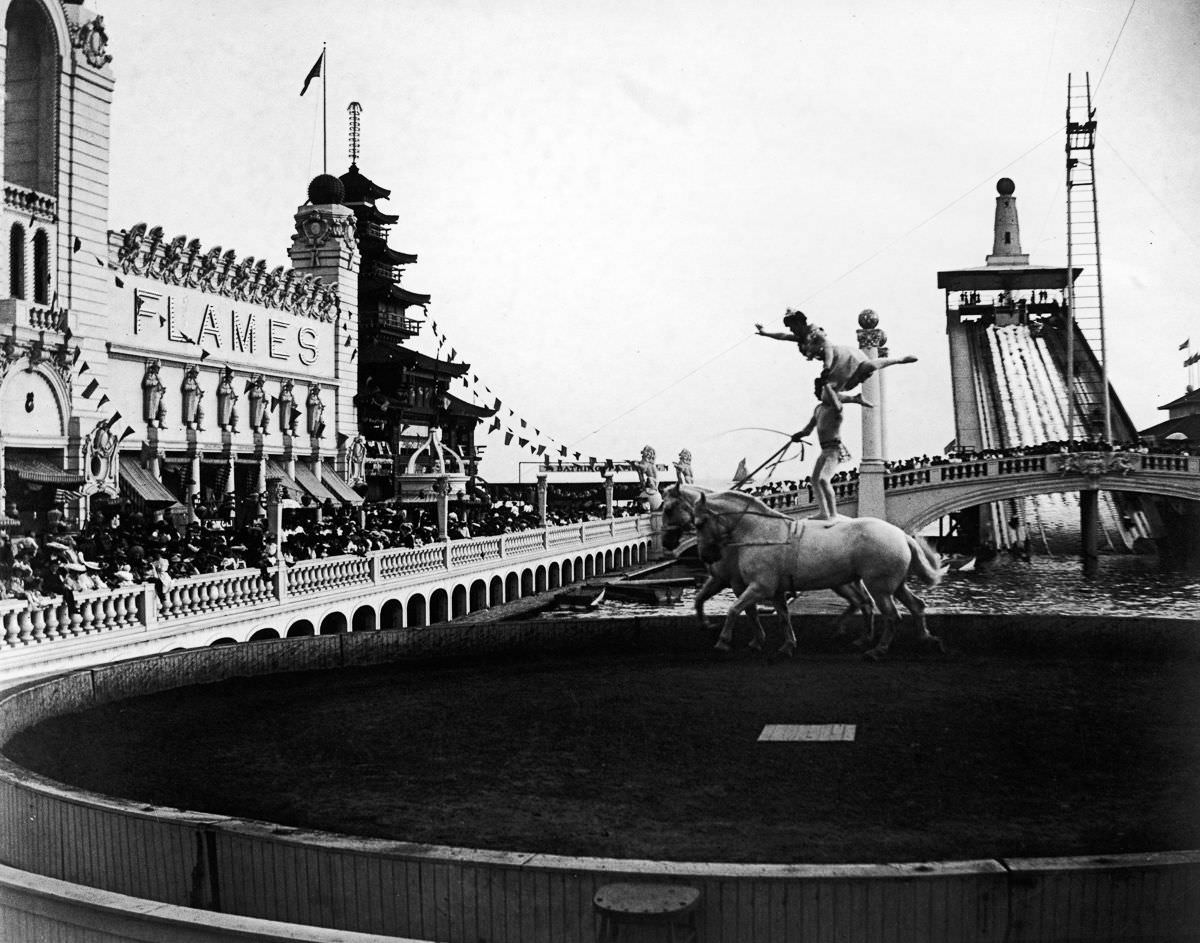 Acrobats perform a balancing act on the backs of a pair of horses as crowds watch at Coney Island’s Dreamland.