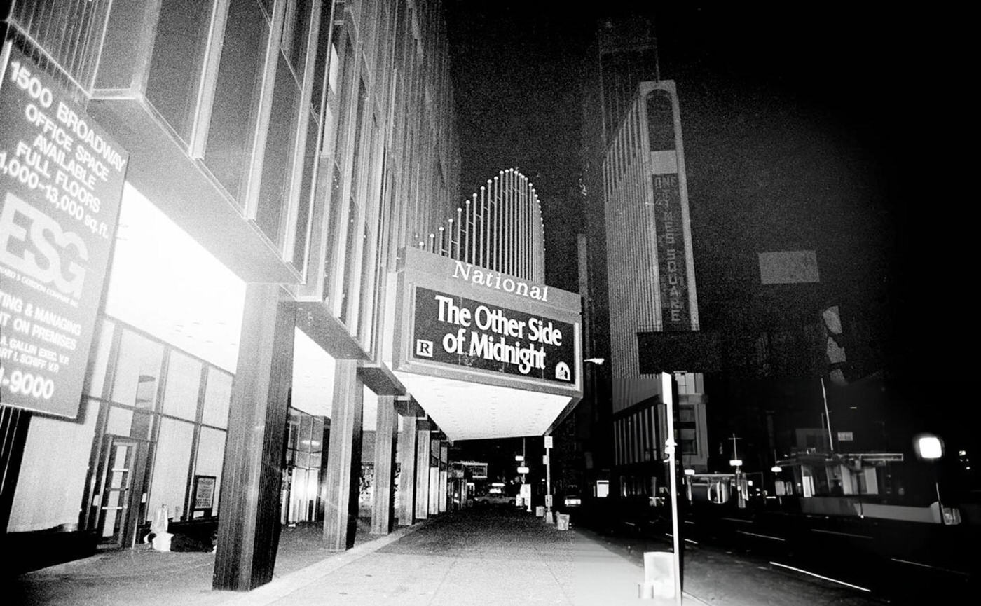 The exterior of the National Theatre on Times Square showing "The Other Side of Midnight" during the New York City blackout, 1977.