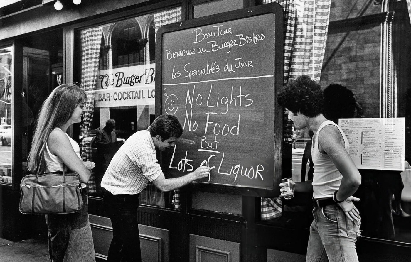 A restaurant owner writes a sign to advise customers about the blackout, 1977.