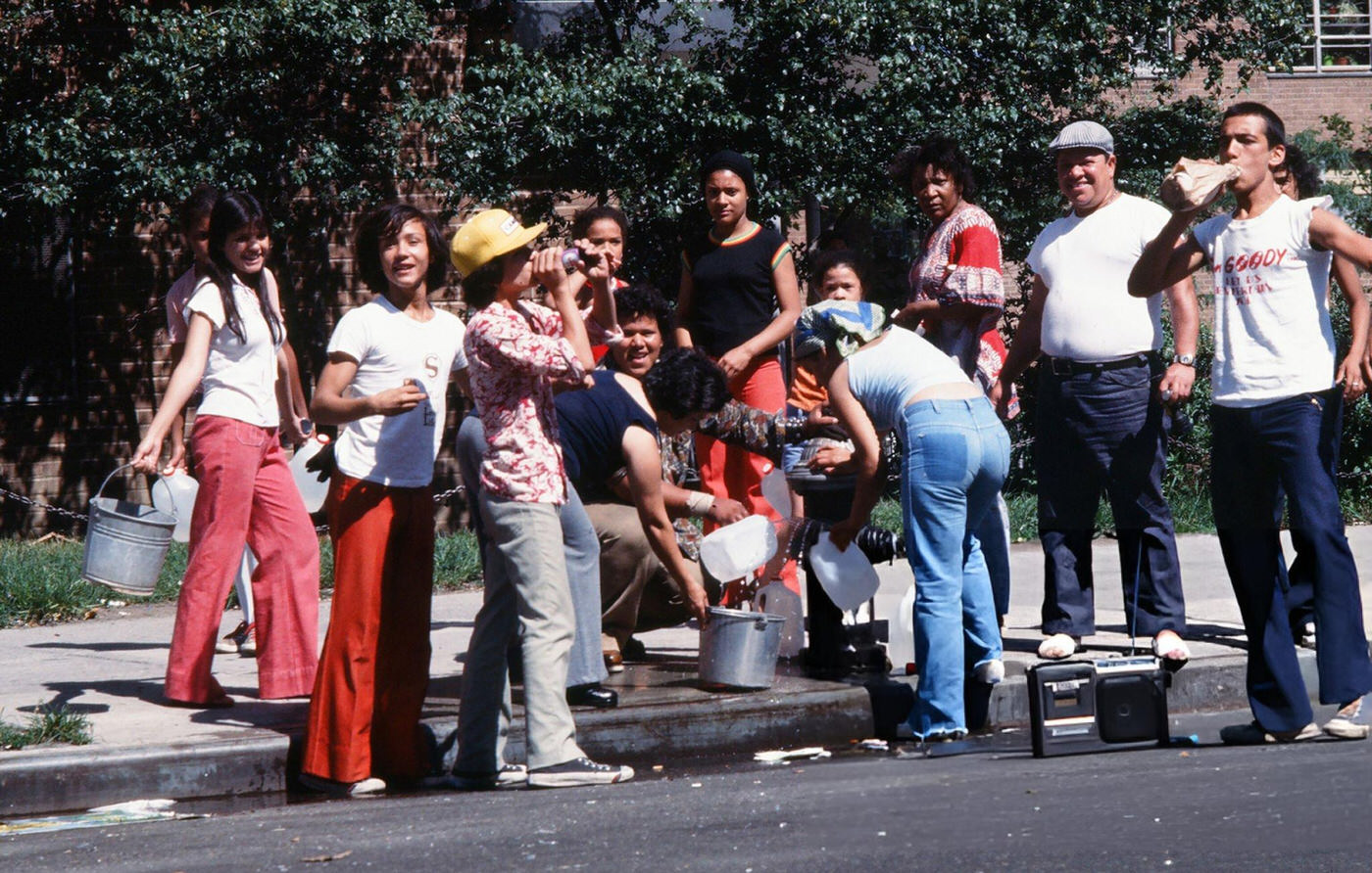 People fill up buckets and bottles from an opened fire hydrant in the wake of the New York City blackout, Brooklyn, 1977.