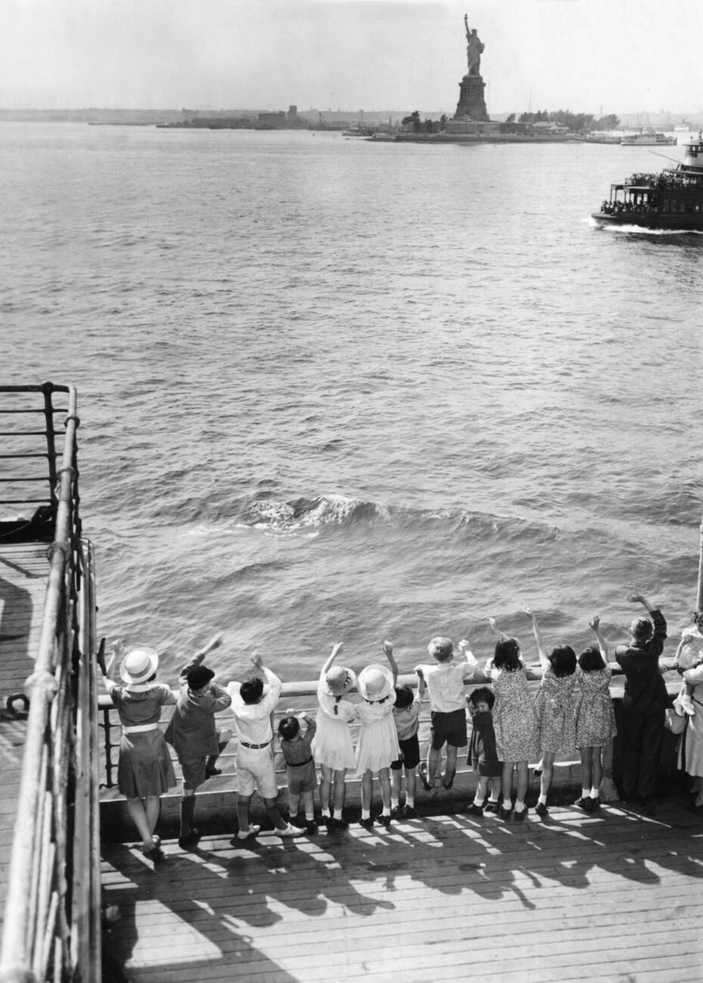 English children who were evacuated to the USA waving to the Statue of Liberty as they arrive in New York City.