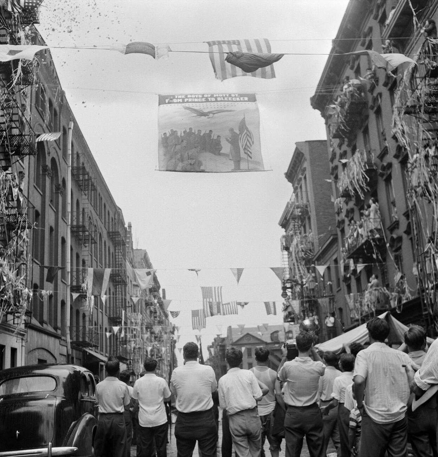 A flag raising ceremony on Mott Street in New York City, in honor of men from the neighborhood in the United States Army, 1942.