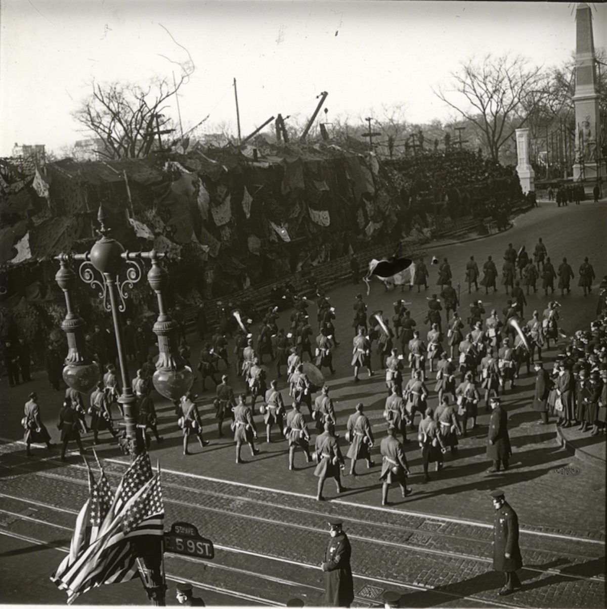 Soldiers on parade, marching north on Fifth Avenue at 59th Street, with a part of the Arch of Jewels visible, .