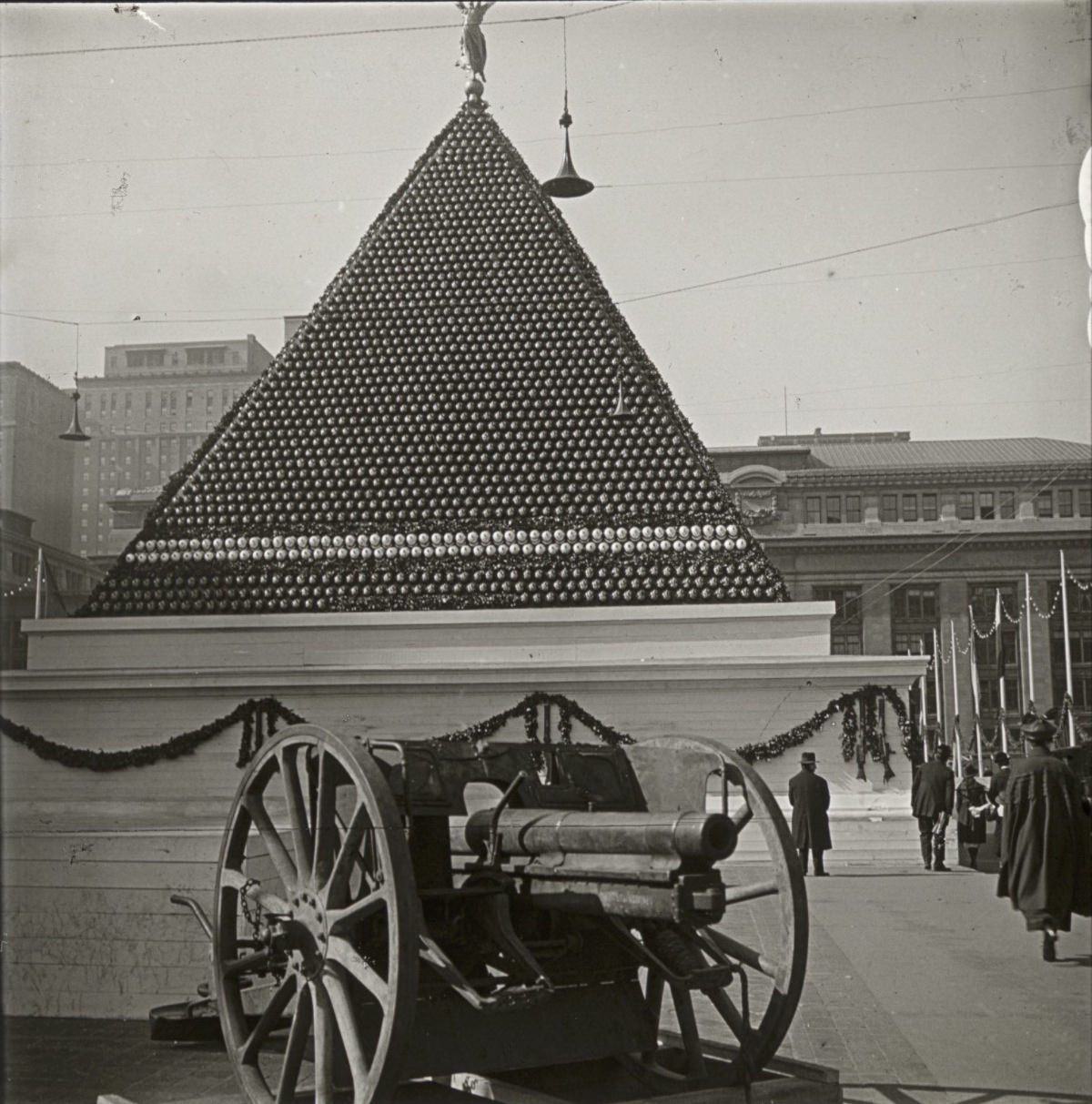 A pyramid built of artillery shells with a gun in the foreground.