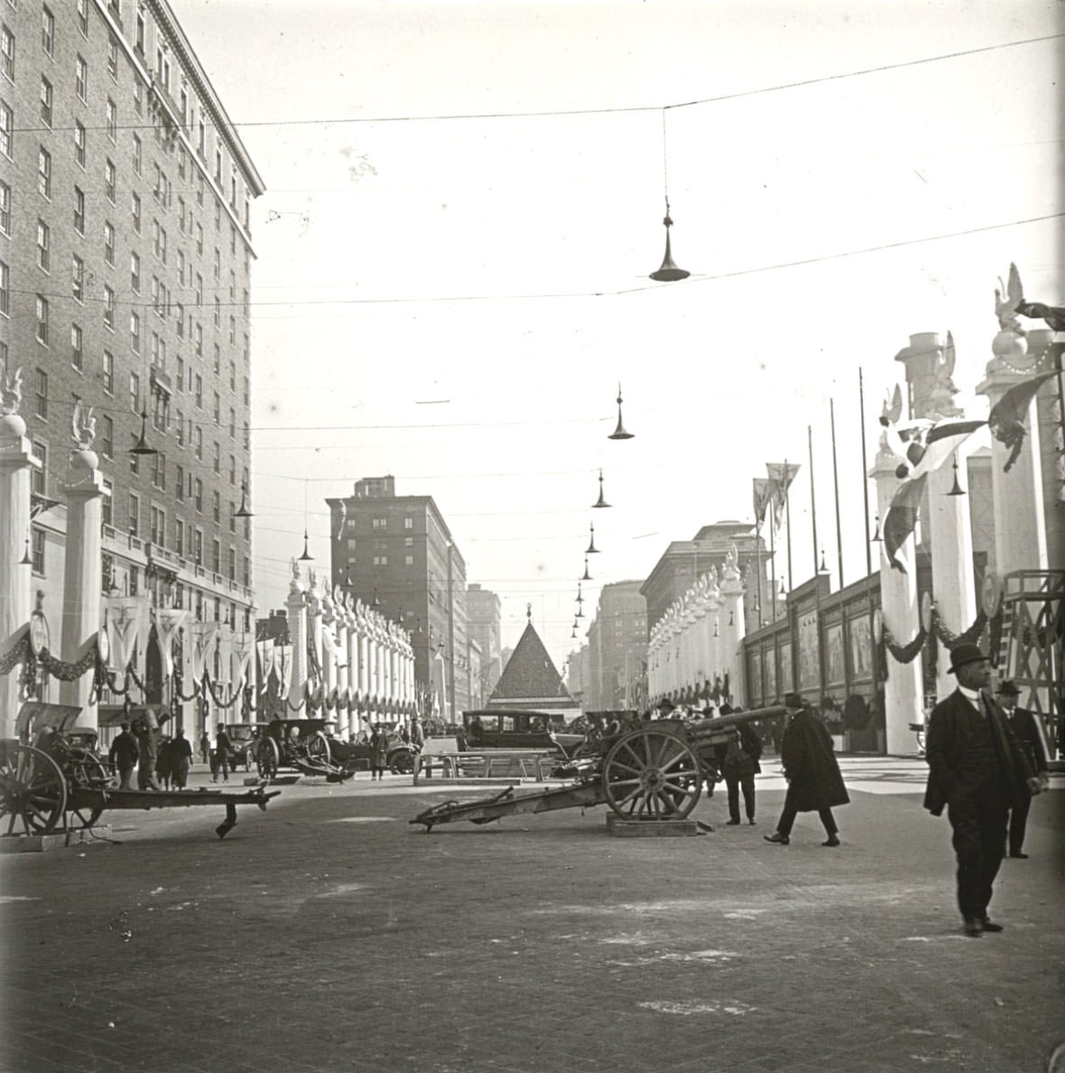 A view on a Manhattan avenue with artillery guns, columns, murals, and a pyramid.