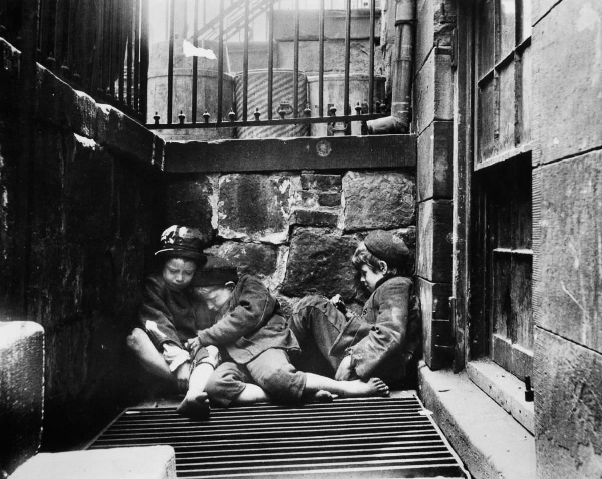 Street children huddle over a grate for warmth on Mulberry Street, 1895.
