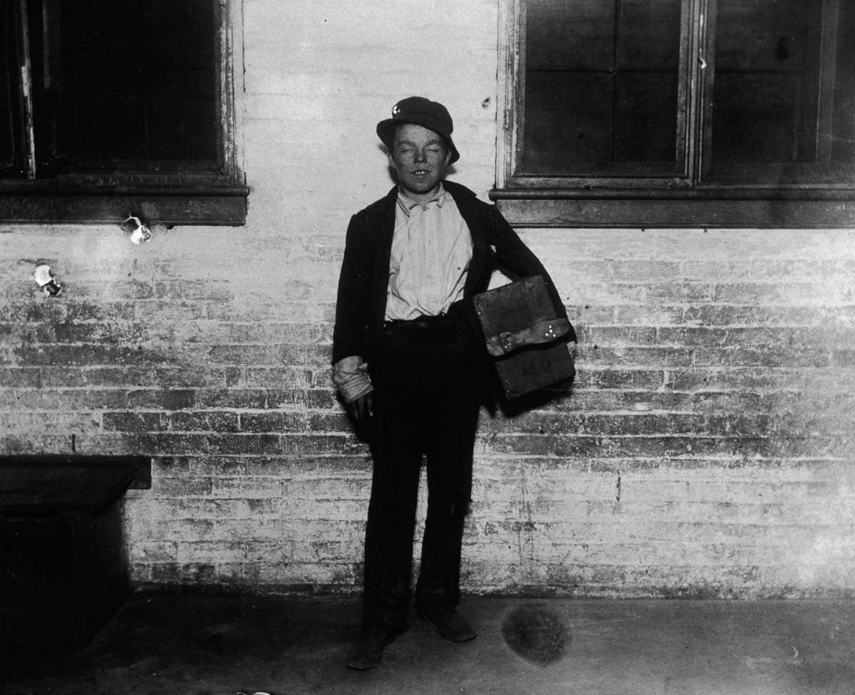 A shoeshine boy named Tommy holds his shoeshine kit on a sidewalk, 1890.