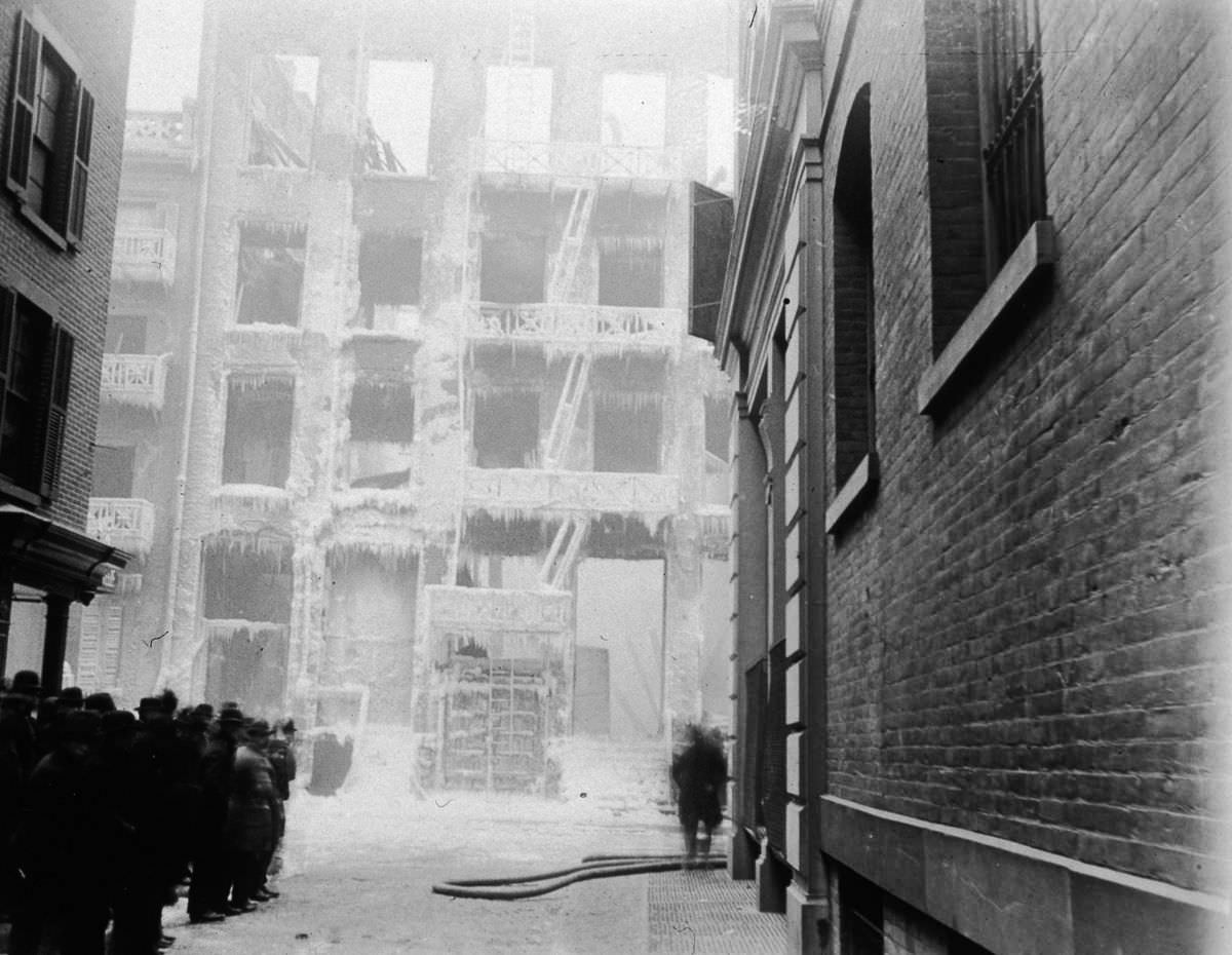 A crowd stands in front of the frozen facade of a burned building on Crosby Street at Jersey Street, 1896.