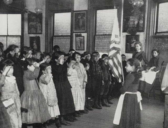 Immigrant children saluting the flag in the Mott Street Industrial School.