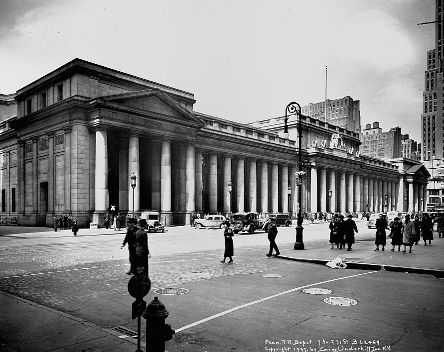 Pedestrians and cars bustle past the doric colonnade of Pennsylvania Station, 1960s.
