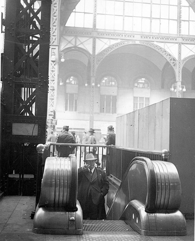 A man approaches the top of an escalator at Pennsylvania Railroad Station, New York, 1940.