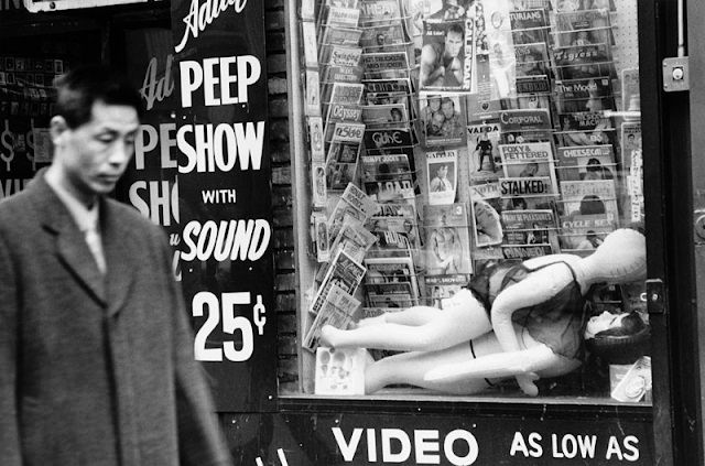 A 25-cent peep show advertises sound-enabled booths—cheap, fast, and anonymous entertainment.