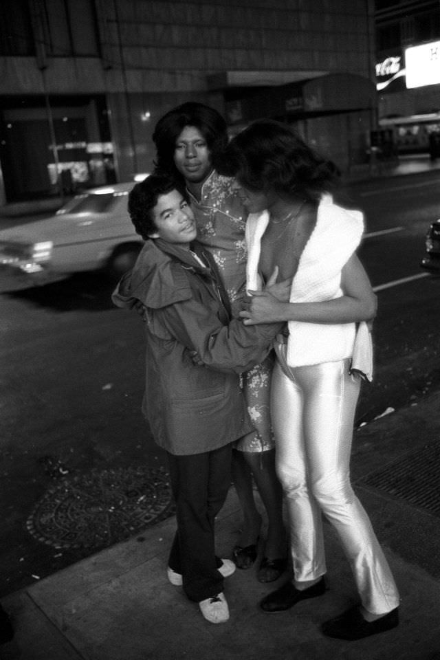 A teenage hustler jokes around with two transvestites on the street.