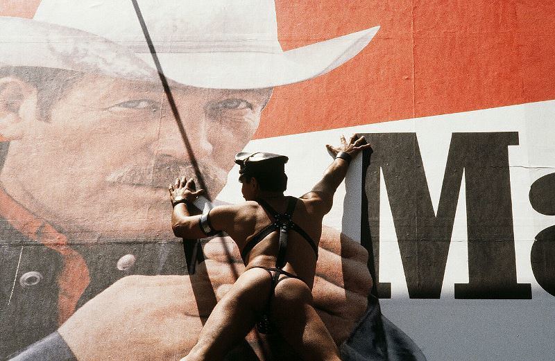 A man wearing only a leather hat and thong climbs a Marlboro billboard on 44th Street, 1980.