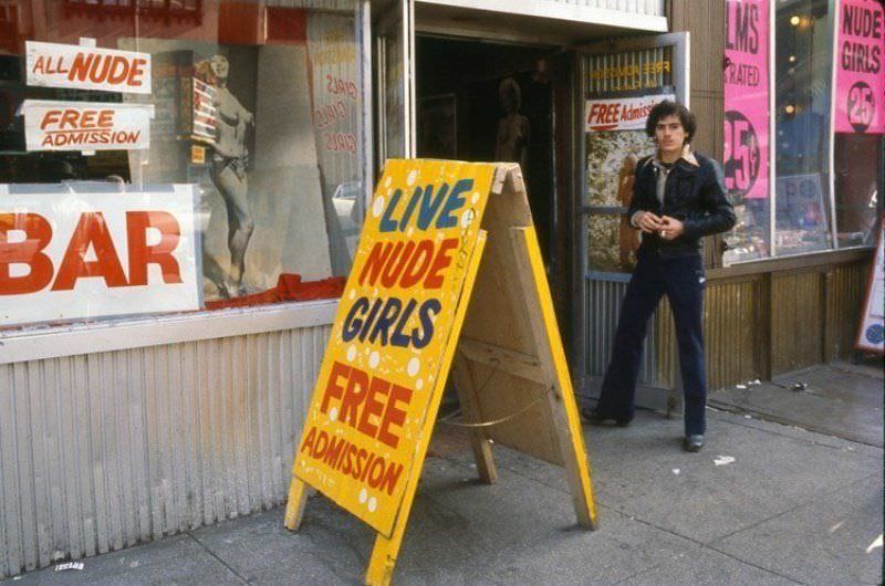 A man stands outside a strip club on 42nd Street in the late 1970s, a common sight at the time.