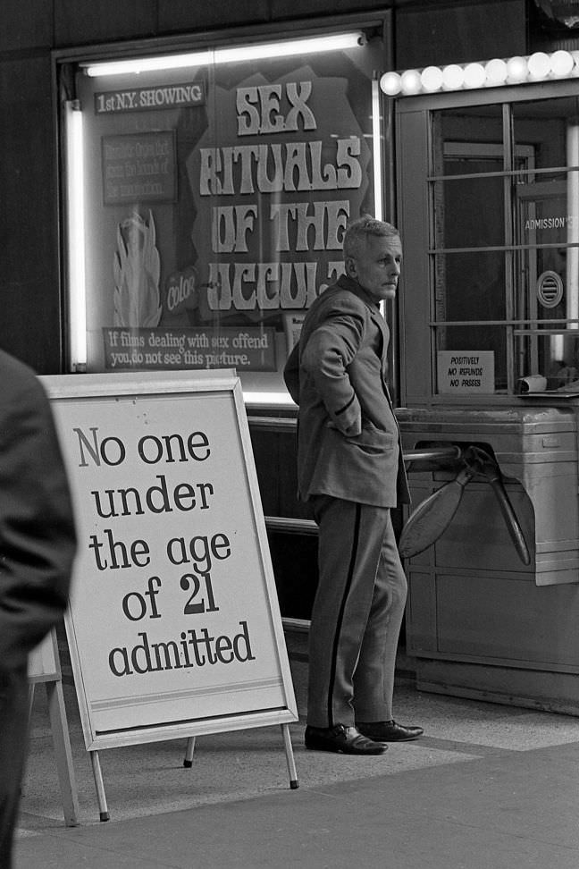 An usher stands at the entrance of a theater screening pornography; only adults over 21 were allowed inside.